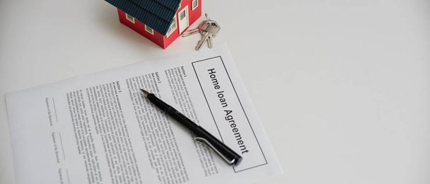 Κάτοψη της συμφωνίας δανείου στο σπίτι με στυλό, μοντέλο σπιτιού και κλειδί σπιτιού σε λευκό τραπέζι - Φωτογραφία, εικόνα