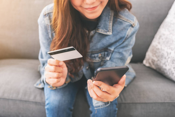 携帯電話でオンラインで購入・買い物をする際にクレジットカードを使うアジア系女性 - 写真・画像