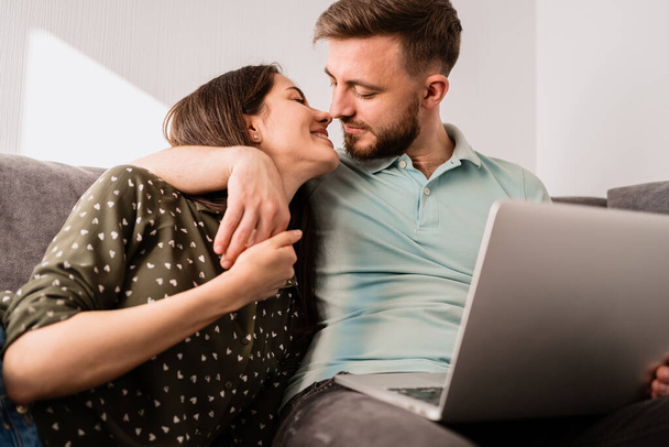 Uomo e donna seduti sul divano con un computer portatile - Foto, immagini