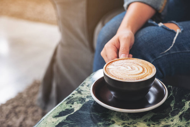 Крупный план руки, держащей чашку горячего кофе на столе
 - Фото, изображение