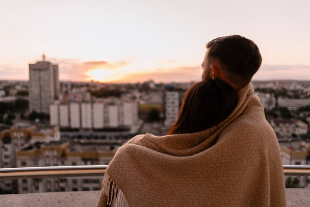 Мужчина и женщина на балконе на закате в городе - Фото, изображение