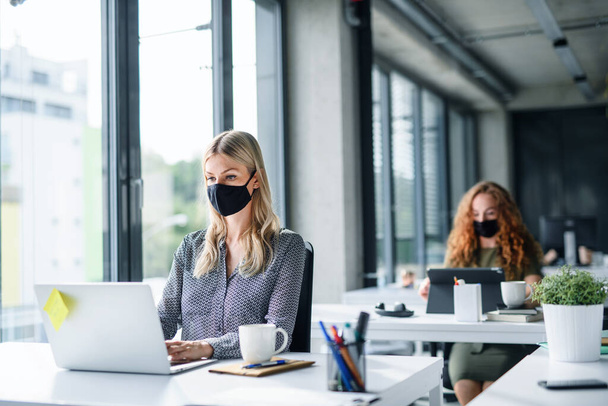 Young people with face masks back at work or school in office after lockdown. - Φωτογραφία, εικόνα