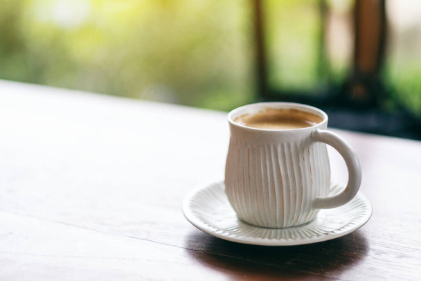 Een witte mok hete koffie op houten tafel  - Foto, afbeelding