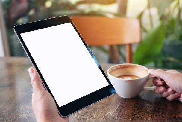 Mockup-Bild einer Frau mit schwarzem Tablet-PC mit leerem weißen Bildschirm und Kaffeetasse zum Trinken - Foto, Bild