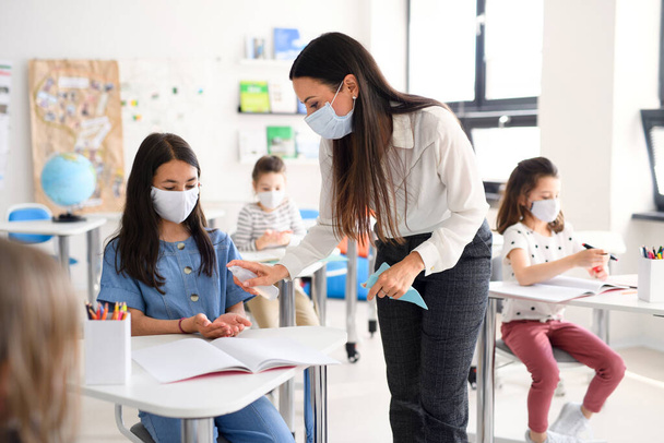 Enseignant et enfants avec masque facial de retour à l'école, mains désinfectantes
. - Photo, image