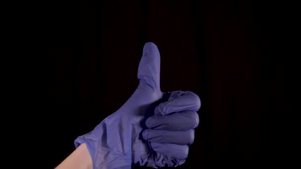 Tento klip ukazuje osobu, která si nasadí modré latexové rukavice a pak dá fotoaparátu palec nahoru gestem na černém pozadí. - Záběry, video