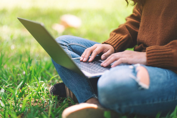 Imagem de close-up de uma mulher trabalhando e digitando no teclado do laptop enquanto está sentado ao ar livre
 - Foto, Imagem