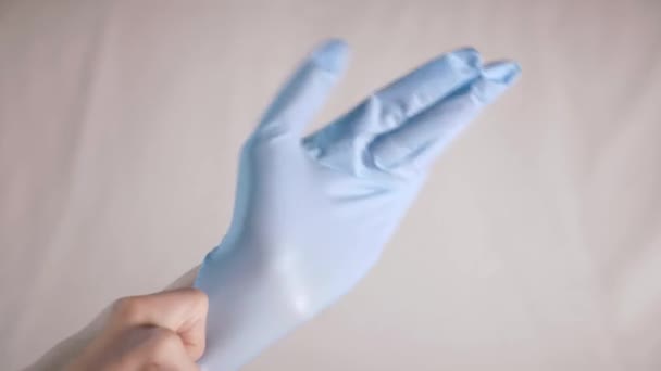Close-up of wearing medical sterile disposable blue gloves on a light white background in the hospital. A doctor or nurse protects your hands from infections and germs. High quality 4k footage - Metraje, vídeo