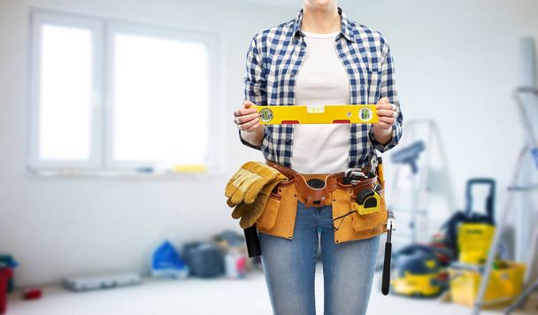 woman builder with level and working tools on belt - Φωτογραφία, εικόνα