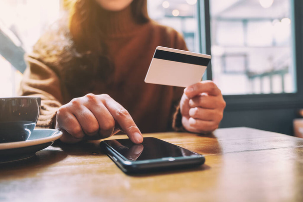 Женщина, держащая кредитную карту и указывая на мобильный телефон для покупки и покупок в Интернете
  - Фото, изображение