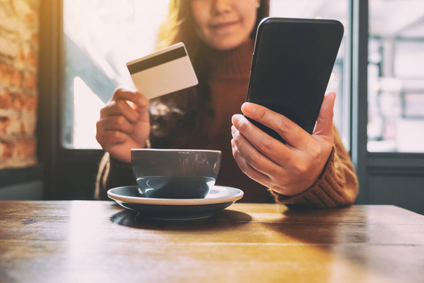 A woman using credit card for purchasing and shopping online on mobile phone - Valokuva, kuva