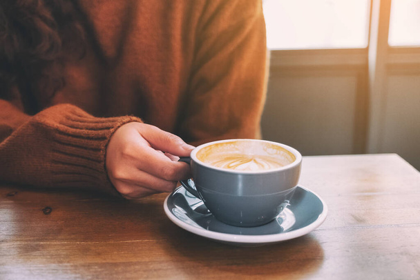 Imagen de cerca de una mujer sosteniendo una taza de café caliente en la mesa
 - Foto, Imagen