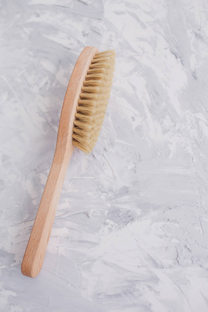Brush for body on a textured gray background. Spa beauty products. Natural material. Massaging salon concept. Flat lay, copy space, top view. Concept skincare organic wooden body skin massage brush.   - Фото, изображение