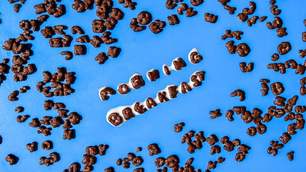 schnelles Frühstück aus Schokoladenflocken in Form von Buchstaben, aus denen MORNING FRÜHSTÜCK mit Milch ausgebreitet wird. Gesunde Ernährung. Draufsicht, flache Lage - Foto, Bild