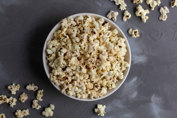 Popcorn in white bowl on grey table. Top view with copy space - Photo, Image