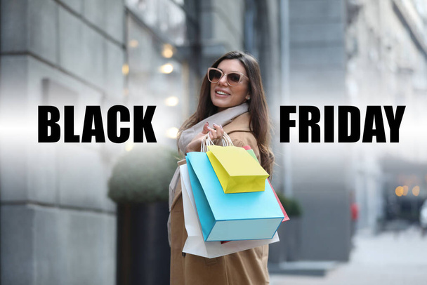Beautiful young woman with shopping bags on city street. Black Friday Sale - Foto, imagen