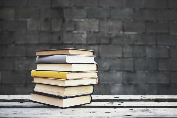 Βιβλία σε ξύλινο πάγκο μπροστά από έναν τοίχο - Φωτογραφία, εικόνα