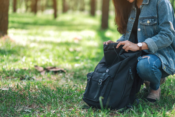 Азиатка-путешественница в шляпе, открывающая рюкзак, путешествуя по красивым сосновым лесам.
 - Фото, изображение