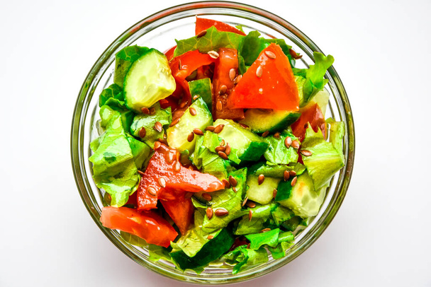 geserveerd bord met verse salade van tomaten, komkommers, saladebladeren en lijnzaad geïsoleerd op witte achtergrond, Bovenaanzicht, Tekstruimte kopiëren, Veganistisch dieetvoedsel - Foto, afbeelding
