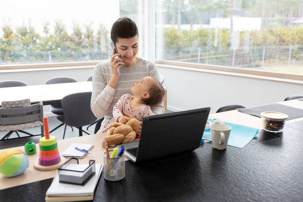 madre con el bebé trabajando en el ordenador portátil en la oficina en casa
 - Foto, imagen