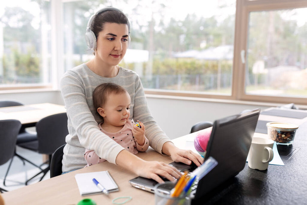 mother with baby working on laptop at home office - 写真・画像