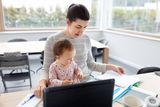 mother with baby working at home office - Foto, afbeelding