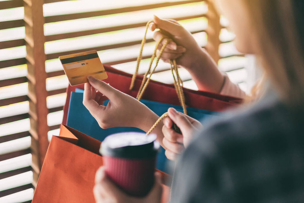 Mujeres con bolsas de compras sosteniendo y utilizando una tarjeta de crédito para la compra
 - Foto, imagen