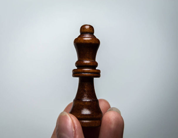 La mano sostiene una pieza de ajedrez. Reina de Ajedrez sobre fondo blanco
 - Foto, imagen