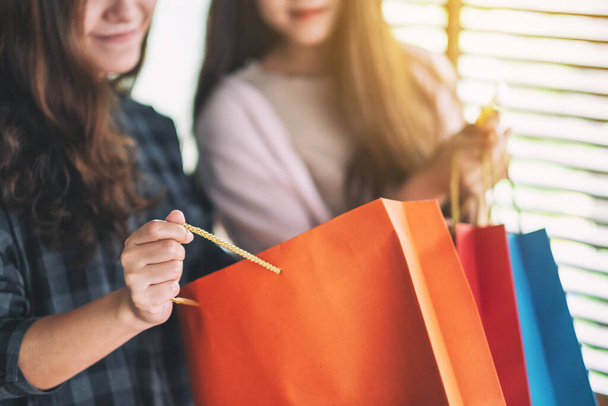 Ženy při otevírání a prohlížení nákupních tašek při držení kreditní karty - Fotografie, Obrázek