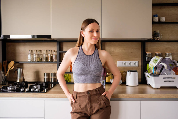 jonge vrouw poseren op moderne keuken achtergrond - Foto, afbeelding