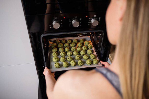 Preciosa mujer poner en el horno una bandeja con falafel
 - Foto, imagen