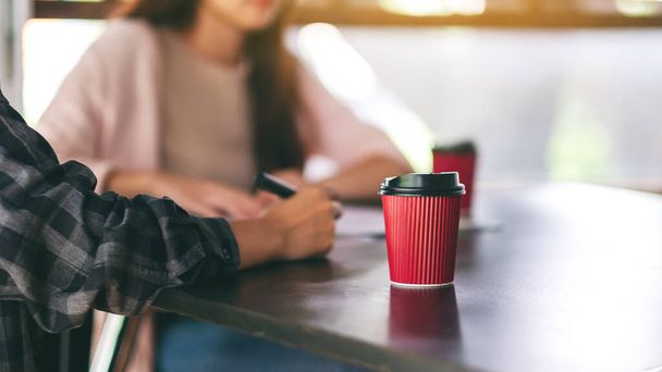Бумажная чашка кофе на столе с бизнесменом в фоновом режиме
 - Фото, изображение