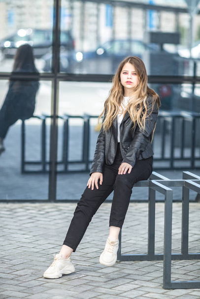 young schoolgirl in black leather jacket posing in the parking lot - Foto, Bild