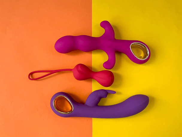 Seks speelgoed. Twee vibrators en wiebelballen op een gele achtergrond. Handig voor seksshop, volwassenen - Foto, afbeelding
