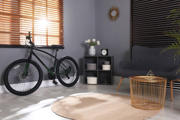 Modern bicycle and comfortable sofa in stylish living room interior - Photo, image