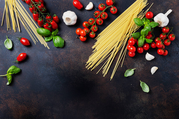 Ingredients for cooking italian pasta: spaghetti, tomato, basil and garlic on the black table. Top view image with a copy space - Foto, Bild