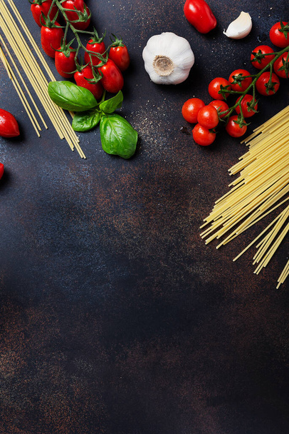Ingredients for cooking italian pasta: spaghetti, tomato, basil and garlic on the black table. Top view image with a copy space - Foto, imagen