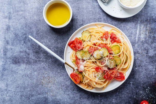 Traditional Italian pasta with tomato, zucchini and parmesan cheese. Concept of healthy vegetarian food. Top down view with copy space - Foto, imagen