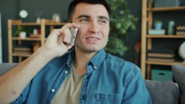 Slow motion of happy adult man speaking on mobile phone in modern apartment - Video