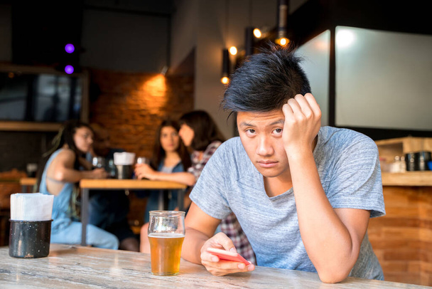 Sad handsome asian man alone in a bar - Фото, зображення