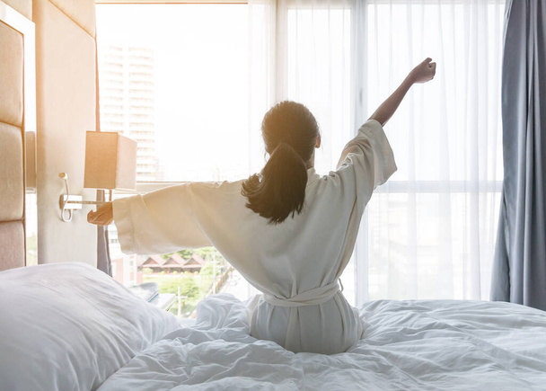 Könnyű életmód fiatal ázsiai lány felébred reggel vesz egy pihenés pihentető hotelszobában a világ lusta nap koncepció - Fotó, kép