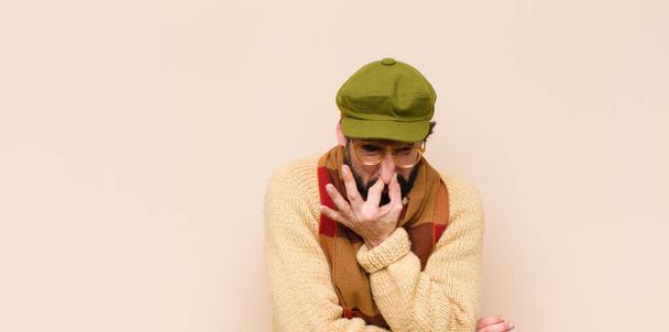 молодий холодний бородатий чоловік відчуває огиду, тримаючи ніс, щоб уникнути нюху і неприємного стені
 - Фото, зображення