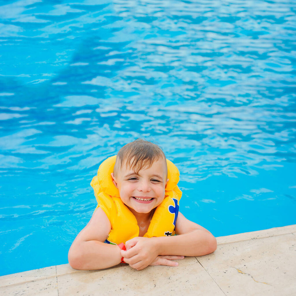 egy 6 éves szőke fiú mentőmellényben egy török szálloda medencéjében. - Fotó, kép