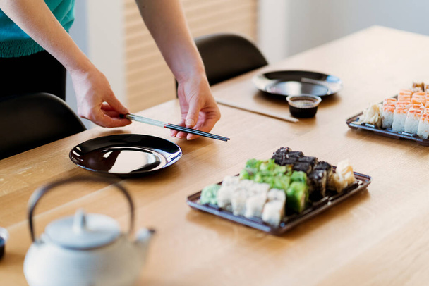 Las manos de la mujer que arreglan los juegos de sushi, los accesorios en una mesa - Foto, Imagen