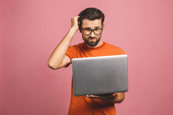 Magabiztos üzleti szakértő. Magabiztos komoly gondolkodó fiatal jóképű férfi ing gazdaság laptop, miközben áll szemben rózsaszín háttér. - Fotó, kép