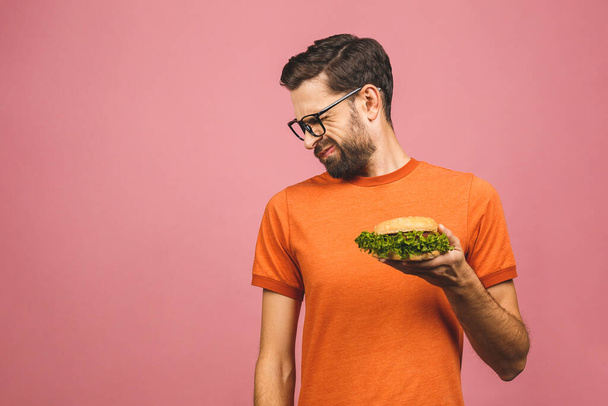 Handsome young man refusing unhealthy burger isolated over pink background. Diet concept. With copy space for text. - Photo, Image