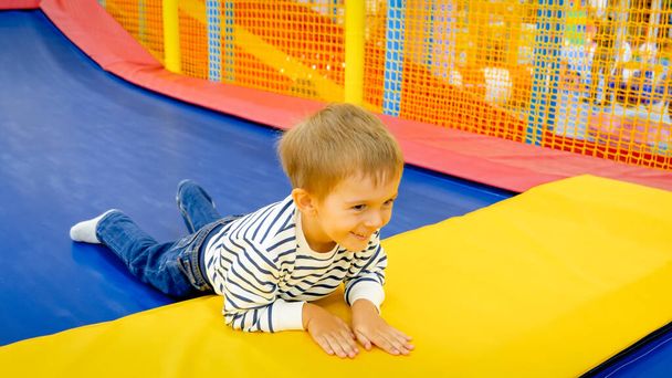 Muotokuva iloinen naurava pieni poika makaa tramploine huvipuistossa - Valokuva, kuva