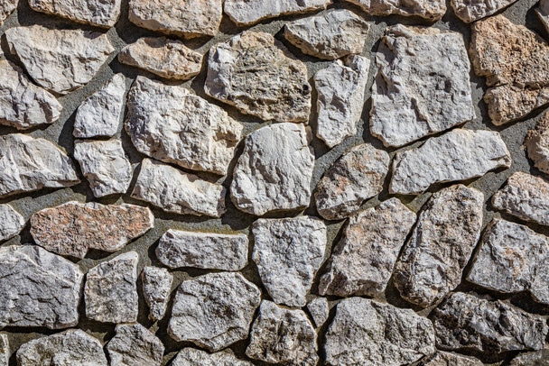 Wall made of cement and irregularly shaped stones. Architectural detail, closeup. Texture, material background. - Photo, Image