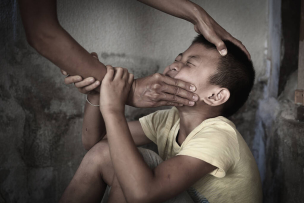 Pelokas poika, jolla on aikuisen miehen käsi peittämässä suutaan. Lopeta väkivallan väärinkäyttö. väkivalta, kauhuissaan, Pelokas lapsi, ihmisoikeuspäivän käsite.  - Valokuva, kuva