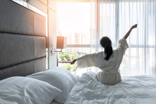 Munka-magánélet minőségi egyensúly koncepció lusta életmód ázsiai lány az ágyon pihentető kényelmes városi hotel hálószoba, nyugi, pihenés a jó alvás ébredés hétvégén reggel, amelynek egy jó nap - Fotó, kép